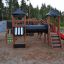 Playground structure Mastodon castle with slide featuring climbing wall, tunnel, and wooden towers.