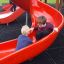 Children playing on red slide of Mastodon castle with slide.