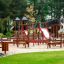 Mastodont wooden playground equipment with slides and climbing structures in a park setting