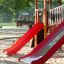 Playground structure with twin red slides on sandy ground, part of the Mastodon castle with slide se