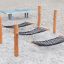 Playground hammocks made of black netting suspended between wooden posts on sandy surface.