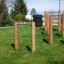 Outdoor playground climbing structure Single Somersault Nature with wooden posts and metal bars.