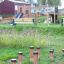 Jumping pegs playground equipment on grassy area with park bench and slide in background.