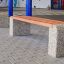Wooden and concrete outdoor bench Wika in front of a building.