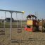 Double Swing Metal Frame and playground structure in a sandy playground.