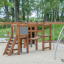 Panther wooden playhouse in a playground with climbing structures and ladders'