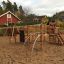 Panther wooden playhouse in a sandy playground with climbing structures and slides.