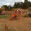 Panther wooden playhouse in a playground with slides and climbing structures.