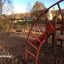 Panther wooden playhouse in a playground with swings and climbing structures in the background