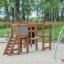 Panther wooden playhouse in a playground with climbing structures and ladders'