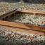 Wooden Sandpit filled with sand in a playground surrounded by autumn leaves.