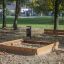 Outdoor wooden Sandpit in a park with a bench nearby