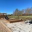 Wooden Sandpit with Attached Slide and Climbing Stairs in an Outdoor Playground.