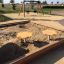 Children's sandpit with yellow seats in a playground.