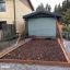 Wooden sandbox with play swings in backyard setting.