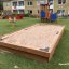 a wooden sandpit on the grass in the residential area