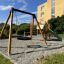 Outdoor playground set with a swing and slide in a garden area.