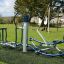 Outdoor fitness equipment Set 8 installed on a playground with green grass and a tree in the backgro