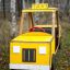 Yellow wooden Taxi playground toy car in a forest setting.