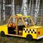 Yellow wooden play Taxi with checkered design parked on grass.