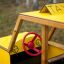 Yellow wooden Taxi playset with red steering wheel.