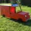 Red toy fire brigade truck on grass.