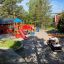 Playground with a wooden Police car structure and colorful playground equipment.