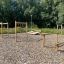 Outdoor playground equipment featuring the Double Jump Bars on a woodchip surface with trees in the 