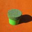 Green jumping peg from the Jumping pegs (5 pcs.) set on an orange surface.
