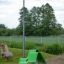 Green Lounge chair on playground grass with wooden animal-shaped seats and a lamp post in the backgr