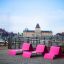 Pink Lounge chair set on a wooden deck with cityscape in the background.