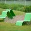 Green Lounge chair made of metal placed outdoors on grass near decorative plants.
