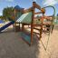 Square Play castle with slide in sandy playground.