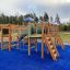 Square Play castle with slide on a blue playground surface in a park.