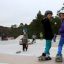Children enjoying skateboarding at an outdoor skate park with ramps.