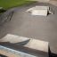 Rail 25/60 skatepark ramp and rail setup on concrete pavement near a brick building.