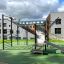 Playground equipment New Age Fit MEDIUM with climbing wall and slide in an outdoor setting.