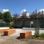 Outdoor sports court with green fences, wooden benches, and basketball hoop, Multiarena.