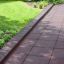 Rubber Tiles 55 playground safety flooring installed along garden path with grass and plants.