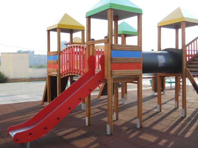 Playground with red slide and wooden structures on Rubber Tiles 55.