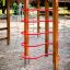 Wooden activity center playhouse with red climbing structures in a sandy playground