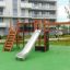Playground equipment Spiderman with slide, climbing net, and ladder in a residential courtyard.