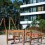 Wooden Obstacle Course with climbing ropes on sandy playground near modern building.