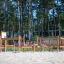 Obstacle Course wooden playground equipment with climbing and balancing features in sandy area.