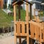 Wooden playhouse with slide 'Rubik Modern Nature' set in a playground area.