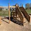 Modern wooden playhouse with climbing net and stairs on playground
