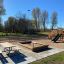 Wooden playground with swings, slide, and sandbox at a park.