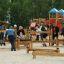 Children and adults playing on Balance playground equipment outside.