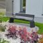 Modern Sydney Bench in a landscaped garden with flowers and greenery.