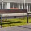 Oxford Bench, modern park bench made of dark wood with metal frame in an urban setting.